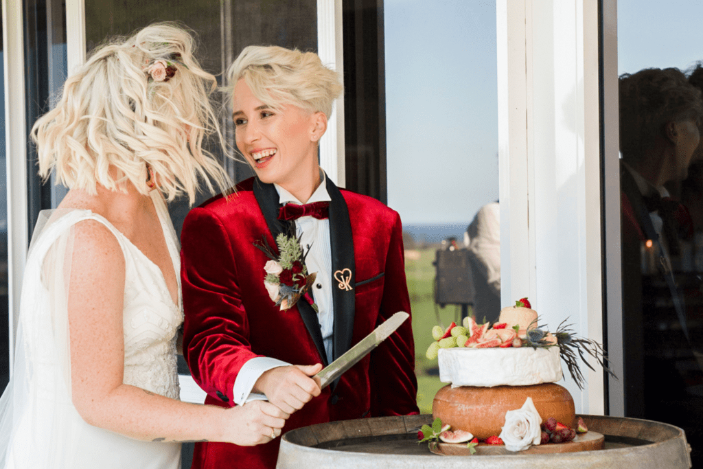same sex wedding bride and bride cutting cake at winery