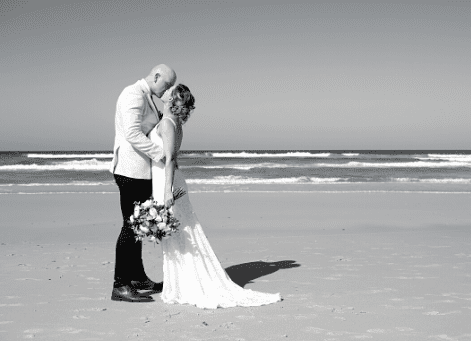 Black and white photo of bride and groom kissing on beach after New South Wales wedding