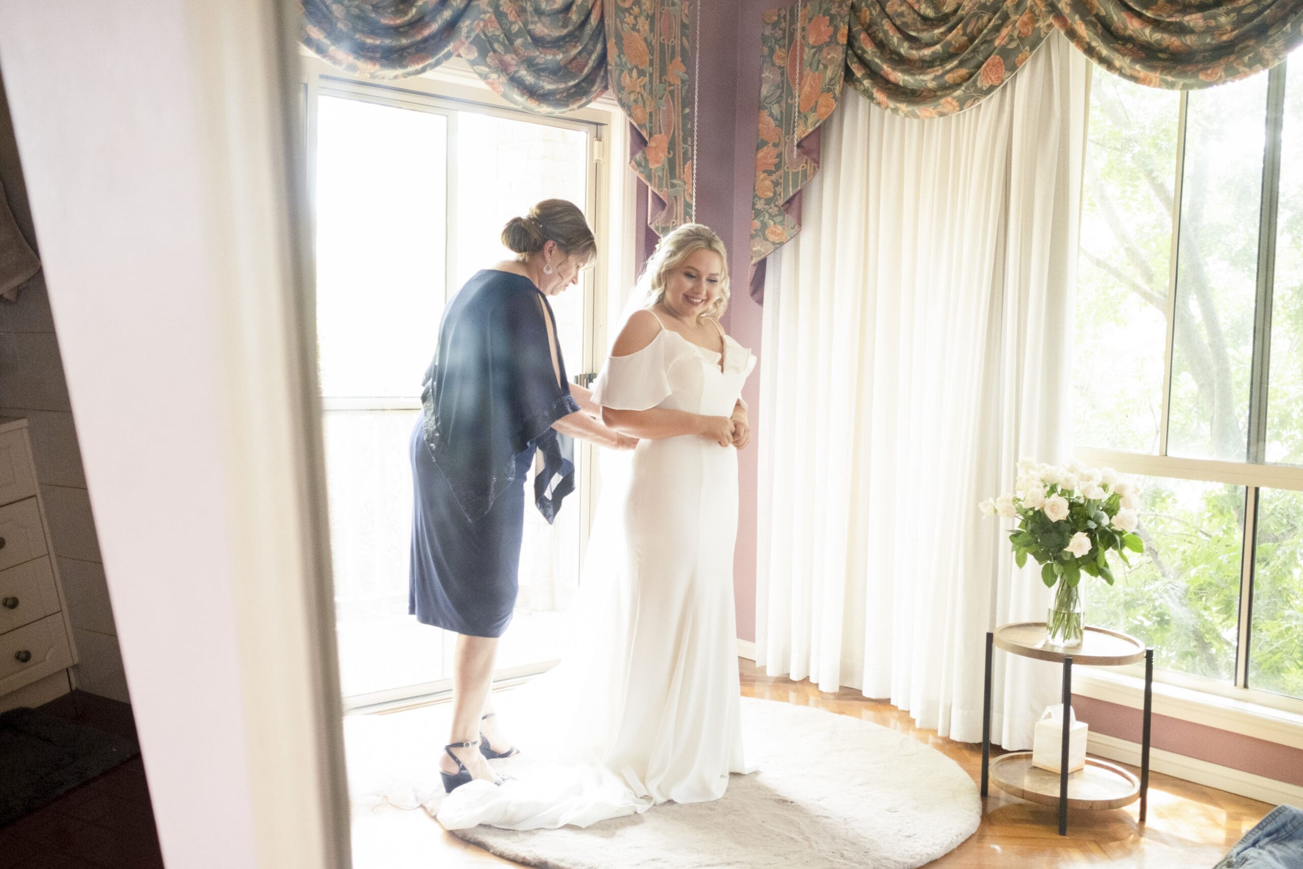 Bride being fitted into slim line dress